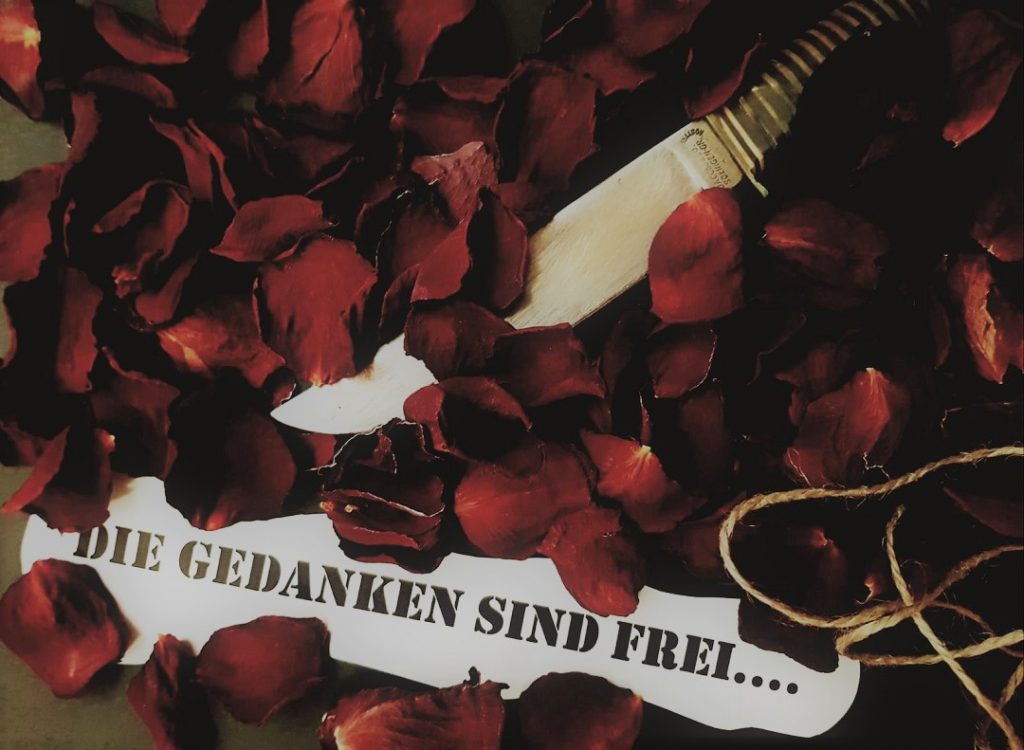 Rosenblätter mit einem Zettel und den Worten "Die Gedanken sind frei"