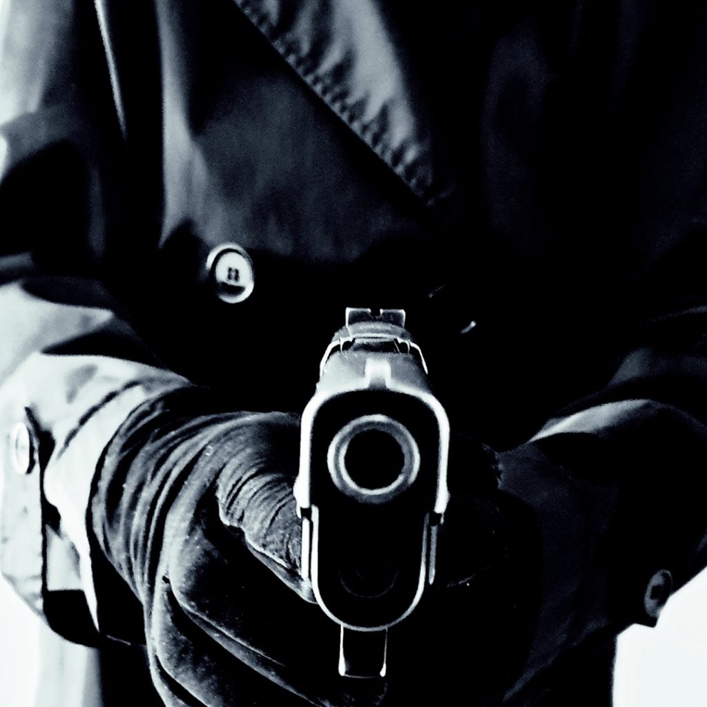 Schwarz/Weiß-Fotografie von einer Hand, die eine Pistole hält